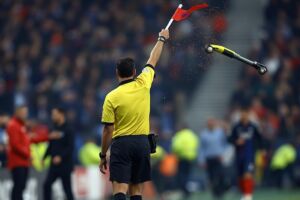 Ritratt maħdum bl-AI juri xena ta' scooter jitwaddab fid-direzzjoni ta' assistant referee.